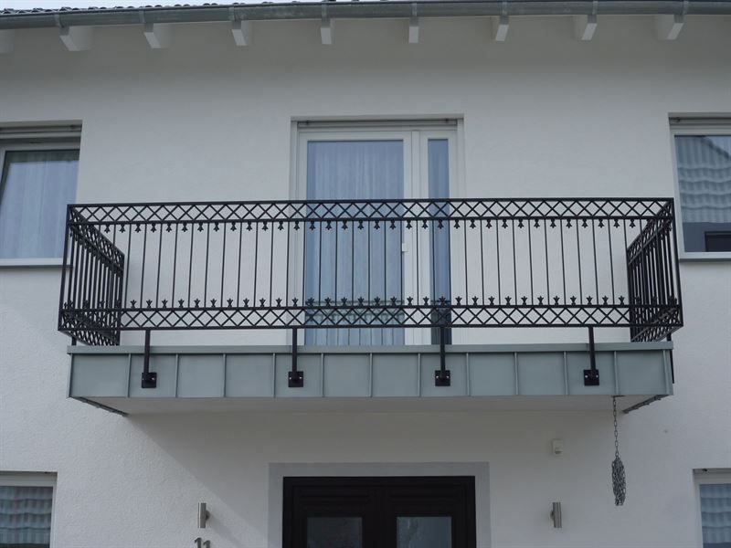 Ein weißes Haus mit einem Balkon und einer schwarzen Tür