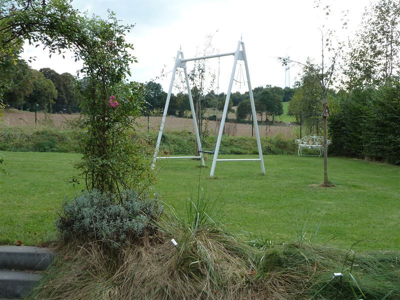 Eine weiße Schaukel steht inmitten eines üppigen grünen Feldes