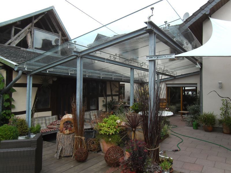 Eine Terrasse mit einem durchsichtigen Dach und einem weißen Sonnenschirm