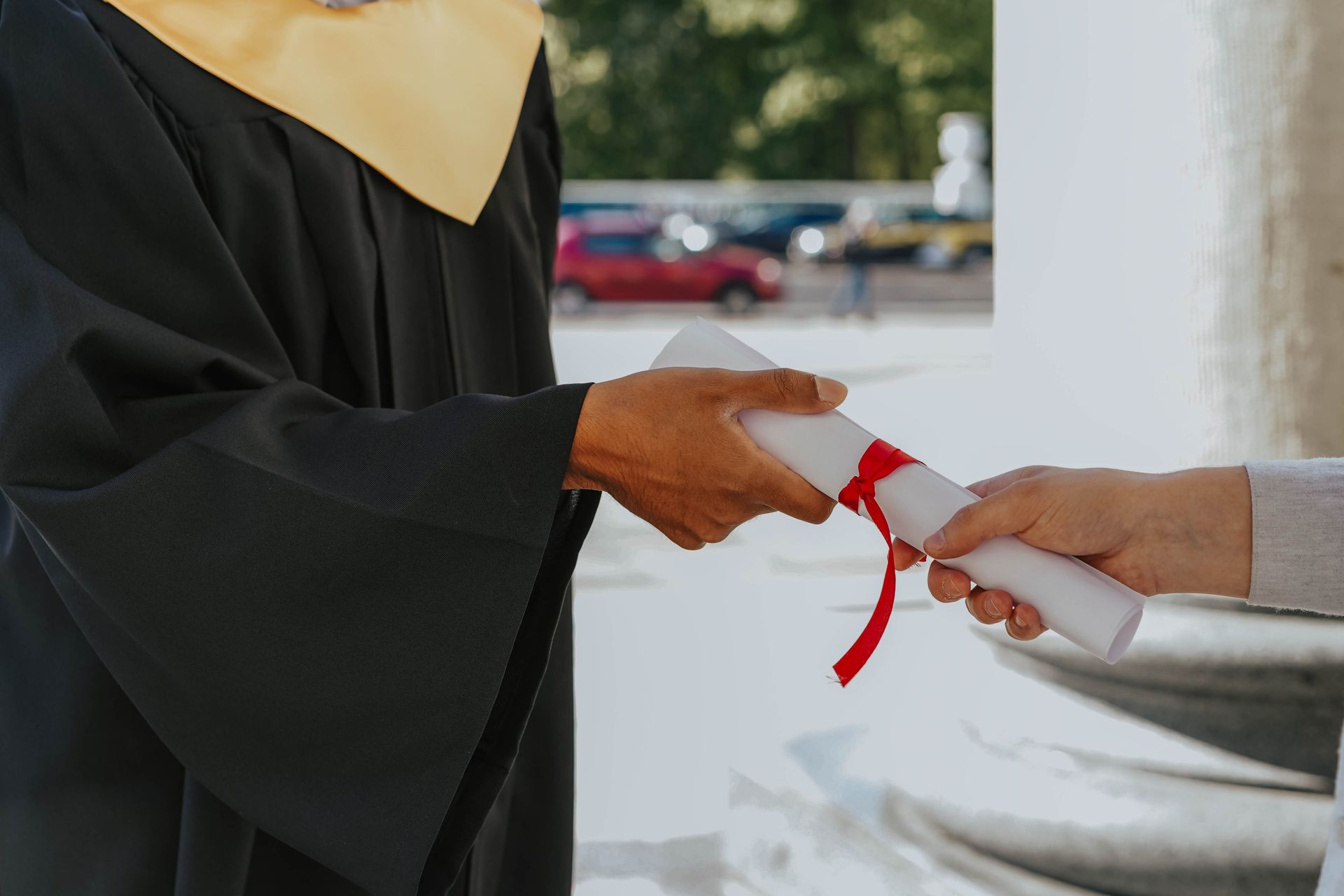 Graduado recibiendo diploma con cinta roja de otra persona