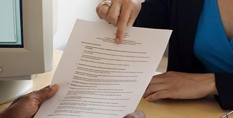 Una mujer señala un trozo de papel con un signo de dólar.