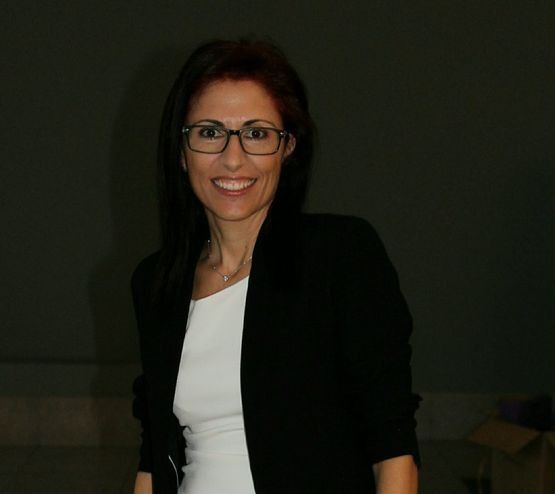 Una mujer con gafas y una chaqueta negra sonríe a la cámara.