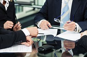 Un grupo de hombres de negocios están sentados alrededor de una mesa mirando papeles.