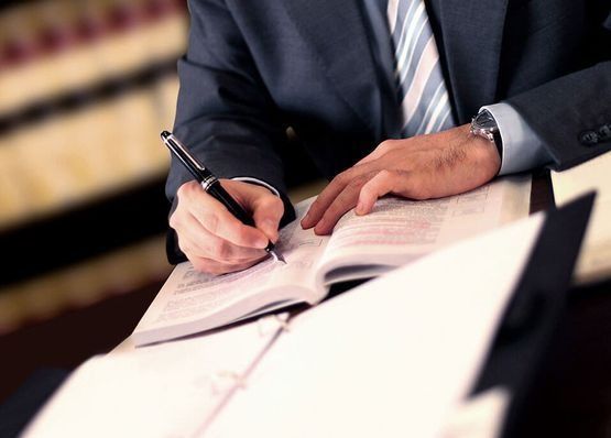 Un hombre con traje y corbata está escribiendo en un libro.
