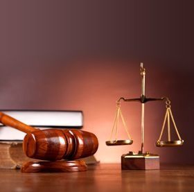 El mazo de un juez y la balanza de la justicia están sobre una mesa de madera.