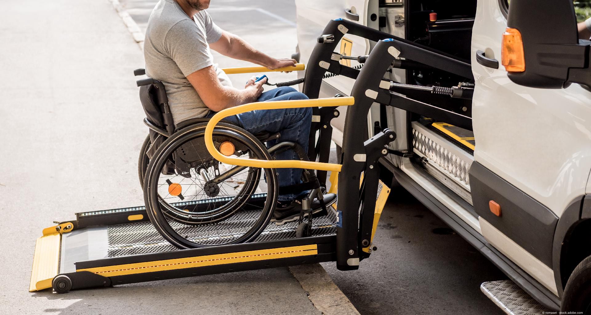 Person im Rollstuhl, die über eine Fahrzeugrampe in ein barrierefreies Transportfahrzeug fährt.