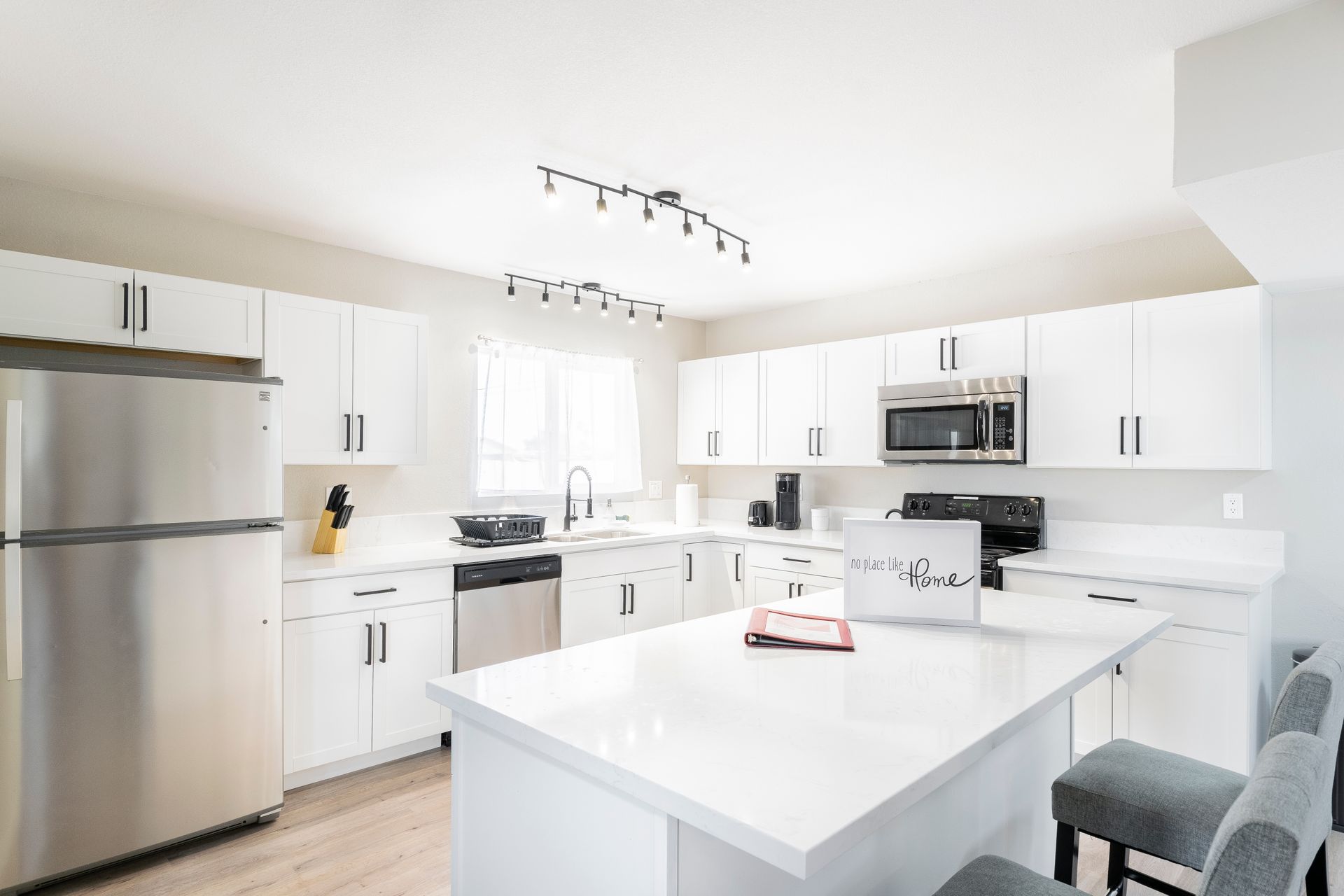 Bright white modern kitchen with stainless steel appliances and a large island
