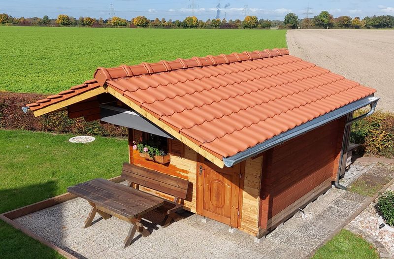 Ein kleines Holzhaus mit einem roten Ziegeldach