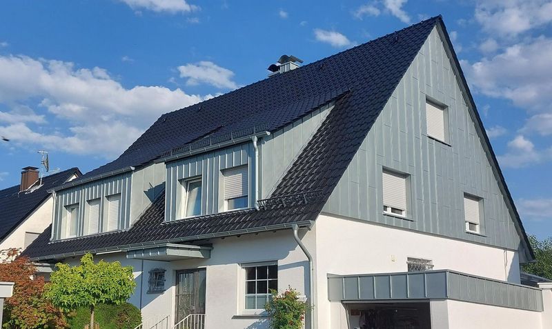 Ein weißes Haus mit schwarzem Dach und blauem Himmel im Hintergrund