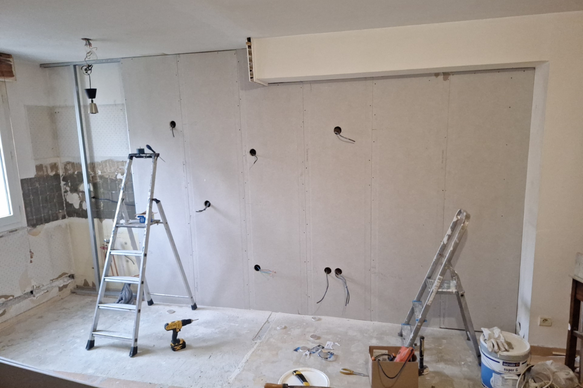 Rénovation intérieure en cours : cloisons sèches sur un mur avec prises électriques.