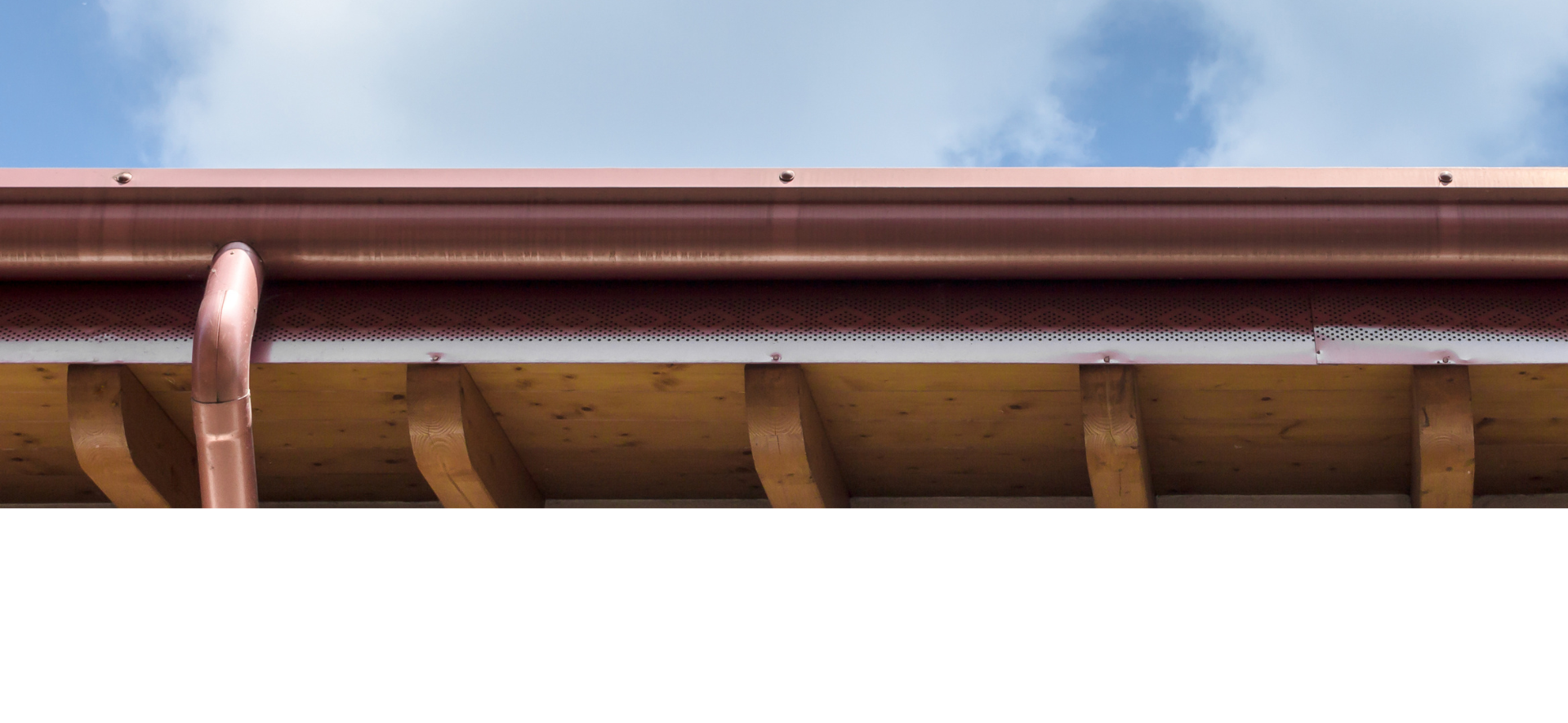 Gouttière couleur cuivre avec descente pluviale, supports en bois et ciel en arrière-plan.