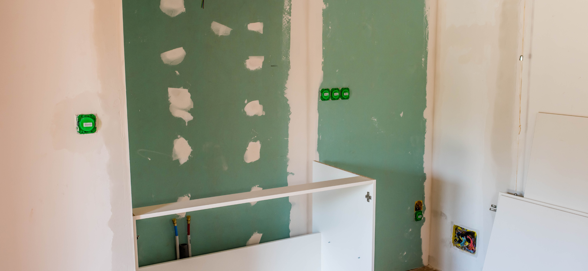Construction de cloisons intérieures avec plaques de plâtre apparentes et prises électriques.