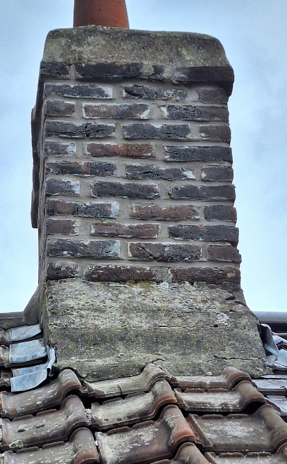 Cheminée en briques sur un toit de tuiles, se détachant sur un ciel nuageux.