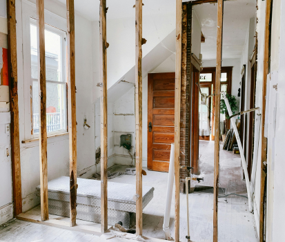 Rénovation intérieure montrant les montants muraux apparents, la porte, la fenêtre et l'escalier.