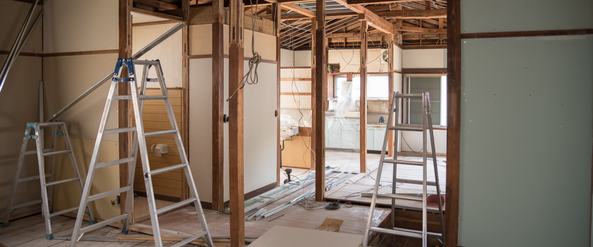 Intérieur d'une pièce en cours de rénovation ; des échelles et des poutres en bois apparentes sont visibles.