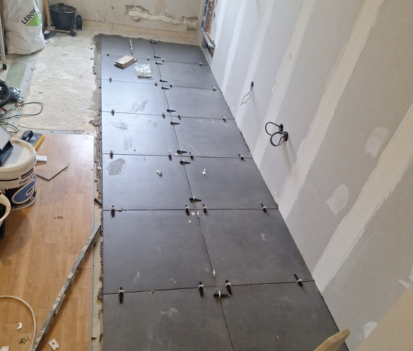 Pose de carreaux de sol gris foncé sur un sol avec des croisillons.
