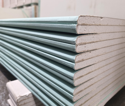 Pile de plaques de plâtre vertes à bords biseautés, prêtes pour la construction.