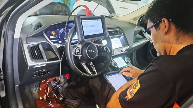 Um mecânico trabalhando embaixo de um carro içado por um elevador em uma oficina mecânica.