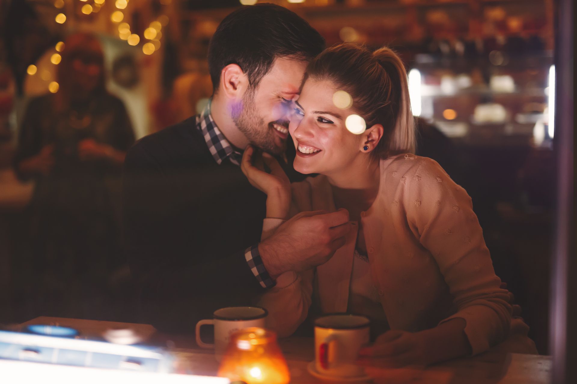 Un couple souriant dans un bar la nuit.
