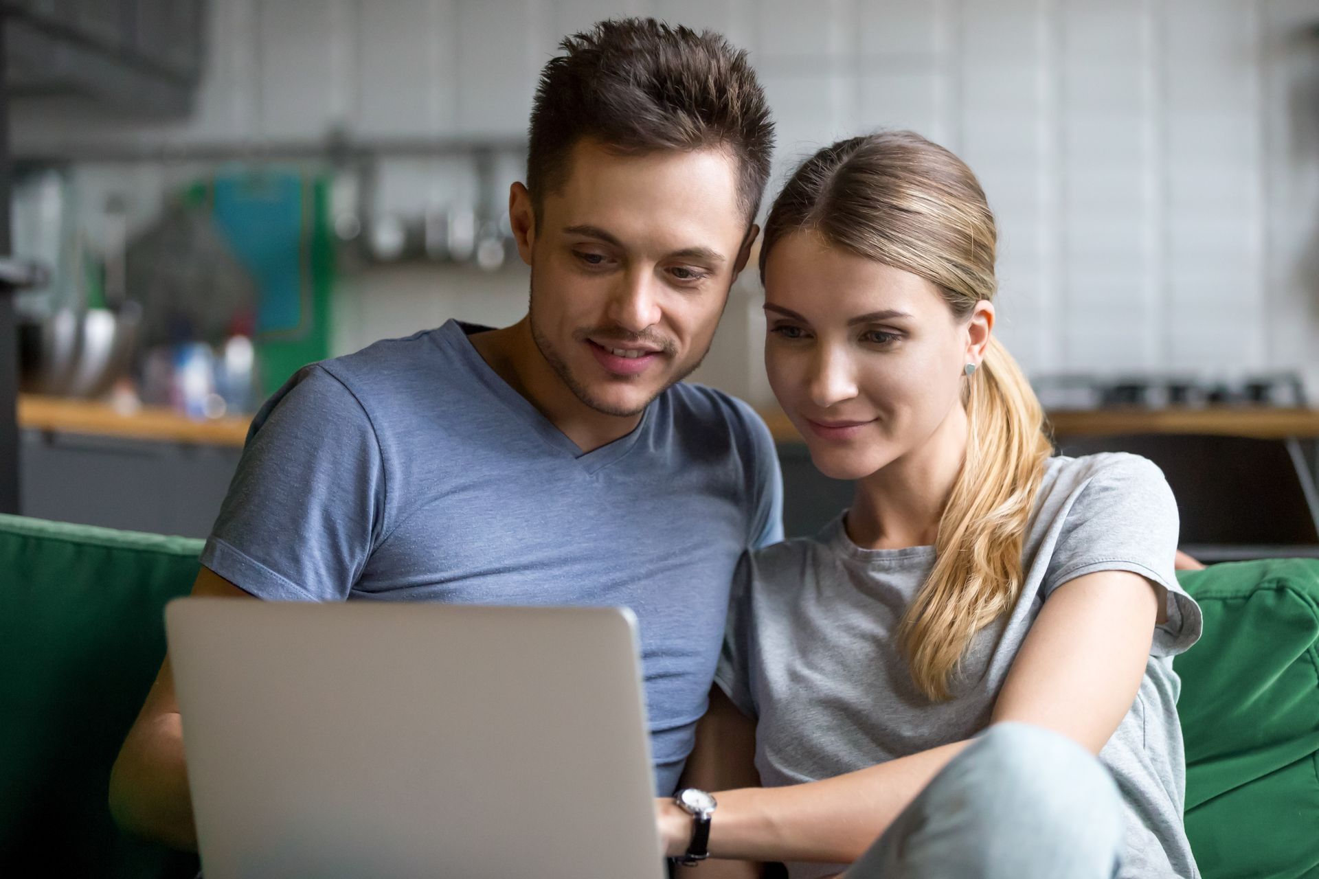 Un homme et une femme sur le canapé en train de consulter un ordinateur portable.