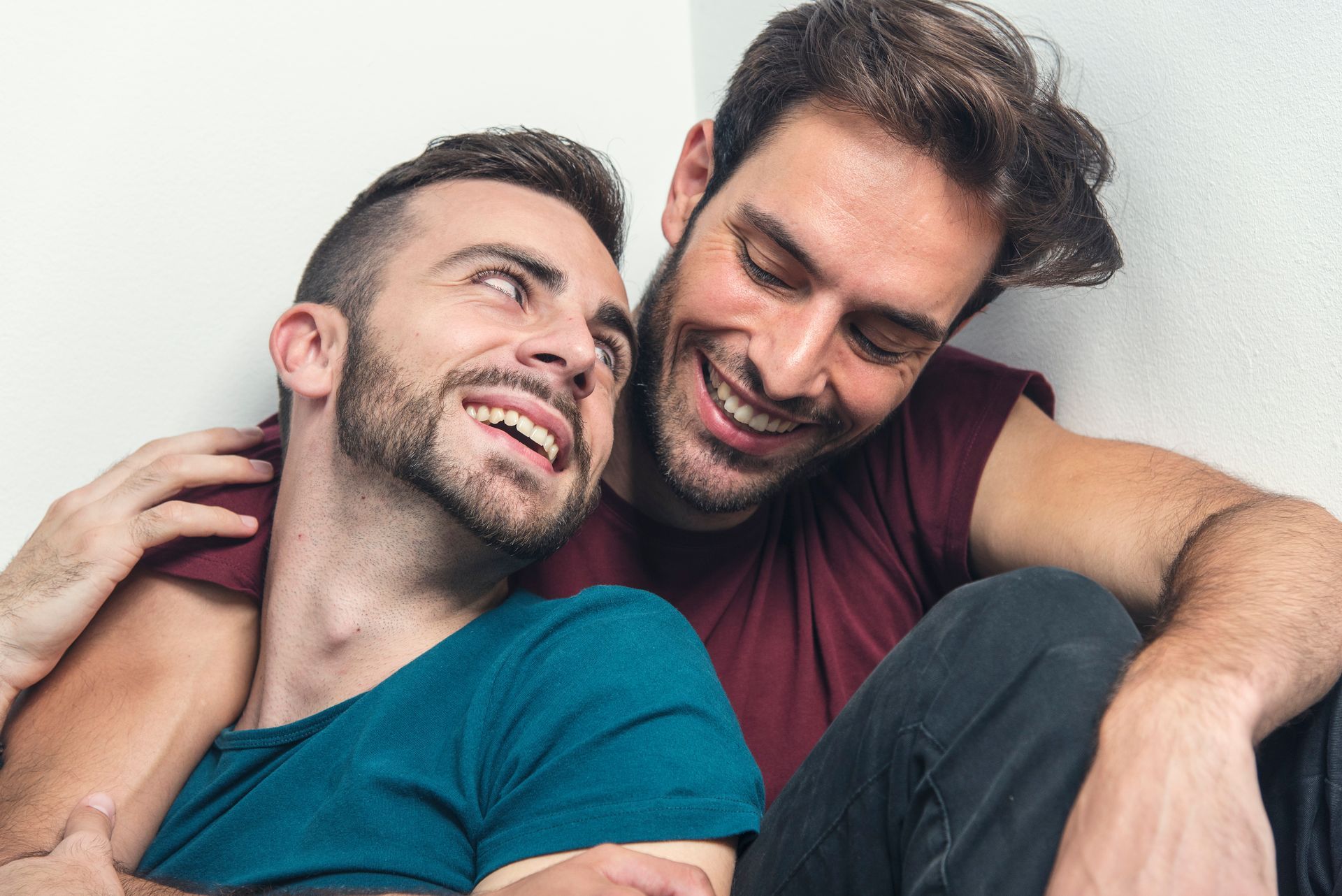 Deux hommes souriant dans les bras l'un de l'autre.