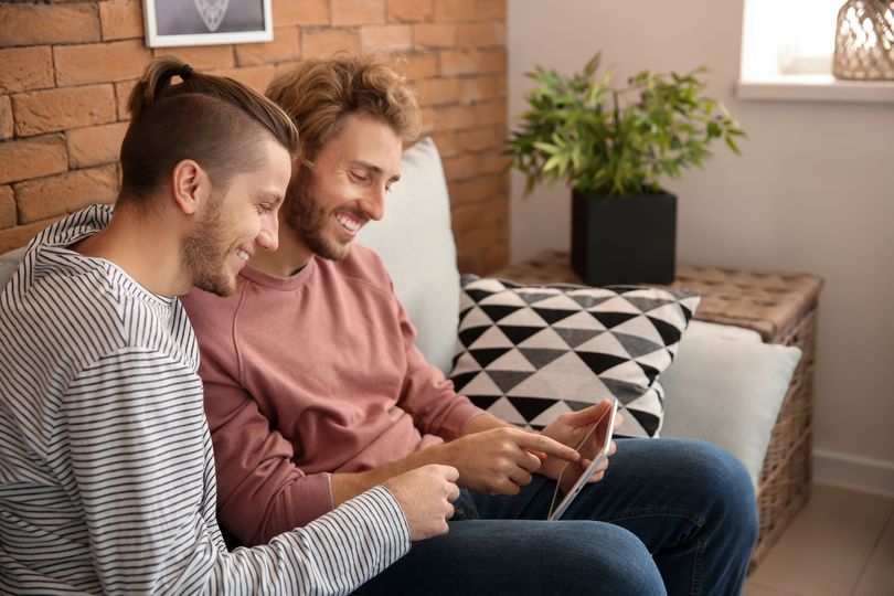 Deux hommes sur le canapé en train de consulter une tablette.