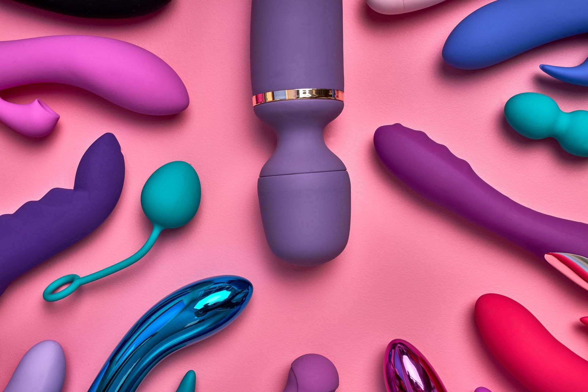 Plusieurs sextoys féminins posés sur un support de couleur rose.