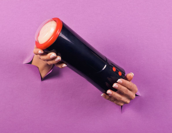 Des mains tiennent un masturbateur noir avec un bord et des boutons rouges.
