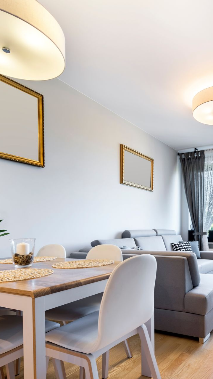 Salle à manger avec une table, des chaises, des œuvres d'art et un canapé gris.