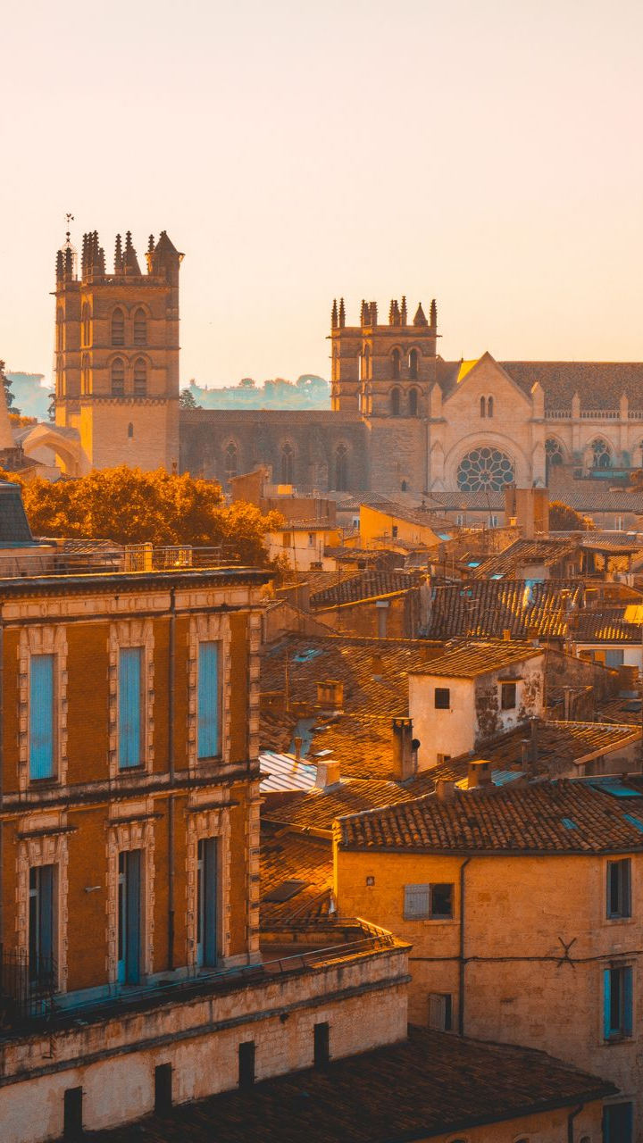 Paysage urbain avec des bâtiments et une cathédrale sous un ciel chaud et doré.