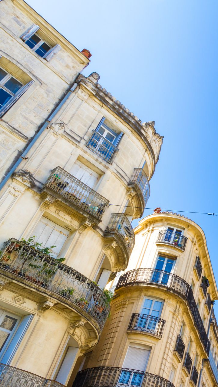 Bâtiments beiges avec balcons sur fond de ciel bleu vif.