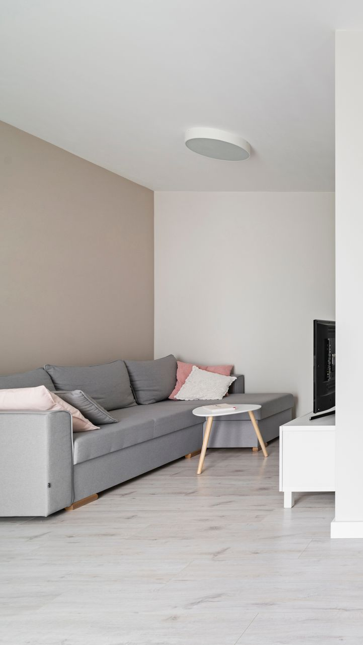 Canapé sectionnel gris dans un salon moderne avec une table basse blanche et une télévision.