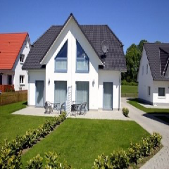 Ein weißes Haus mit schwarzem Dach steht neben einem anderen weißen Haus