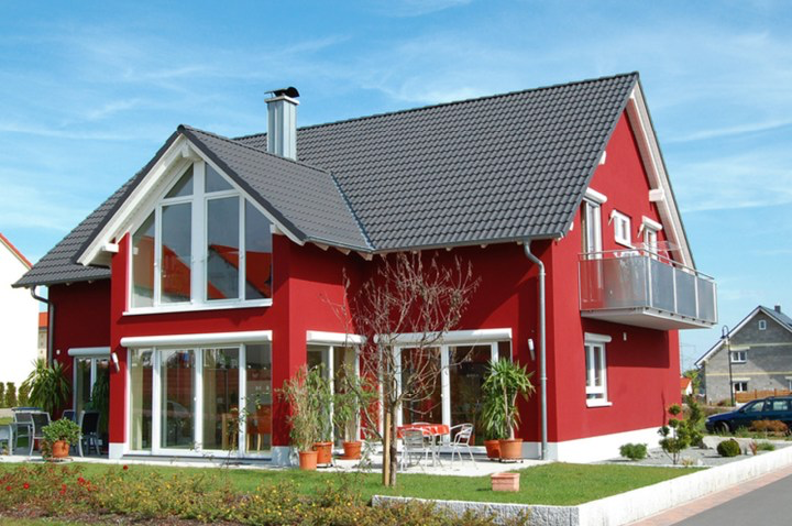 Ein rotes Haus mit einem grauen Dach und vielen Fenstern