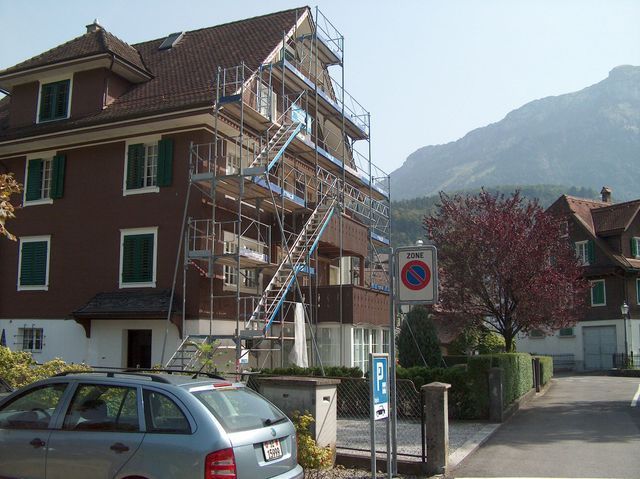 Regli Maler GmbH – Konstruktionsgerüst mit Treppenzugang, umgeben von Schutznetzen, an der Seite eines Wohngebäudes