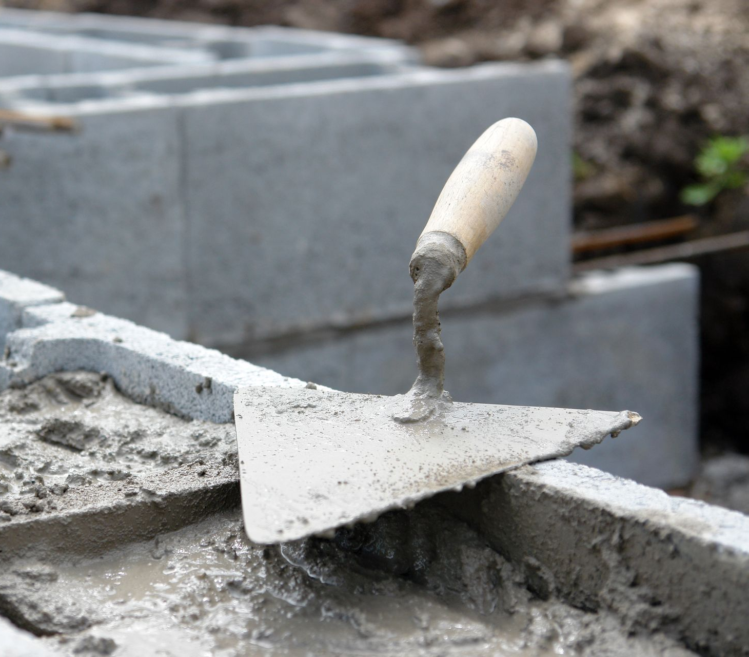 Truelle dans le mortier humide sur des parpaings; chantier de construction.