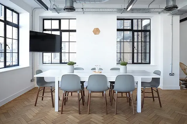 Una sala de conferencias con mesa y sillas y un televisor de pantalla plana.