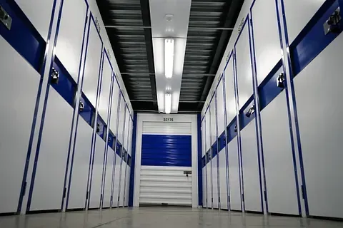 Un largo pasillo con casilleros azules y blancos y una puerta azul.