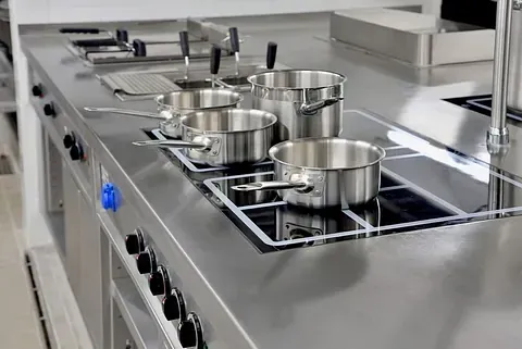 Una fila de ollas y sartenes colocadas encima de una estufa en una cocina.