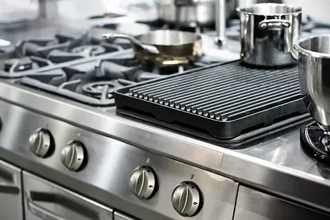 Una estufa de acero inoxidable con ollas y sartenes encima en una cocina.