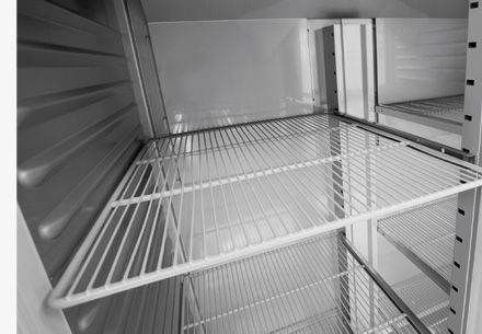El interior de un refrigerador vacío con estantes de alambre.