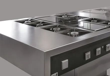 Una estufa de acero inoxidable con cuatro quemadores y fondo gris.