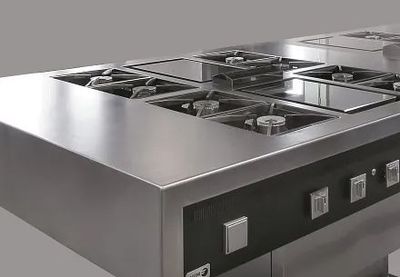 Una estufa de acero inoxidable con cuatro quemadores y fondo gris.