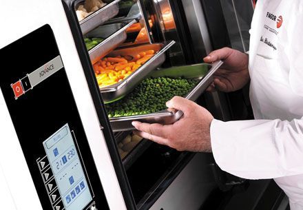 Un chef está sacando verduras de un horno que dice sincronizar.