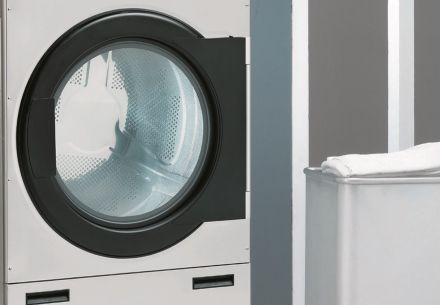 Una lavadora y una secadora están una al lado de la otra en una lavandería automática.
