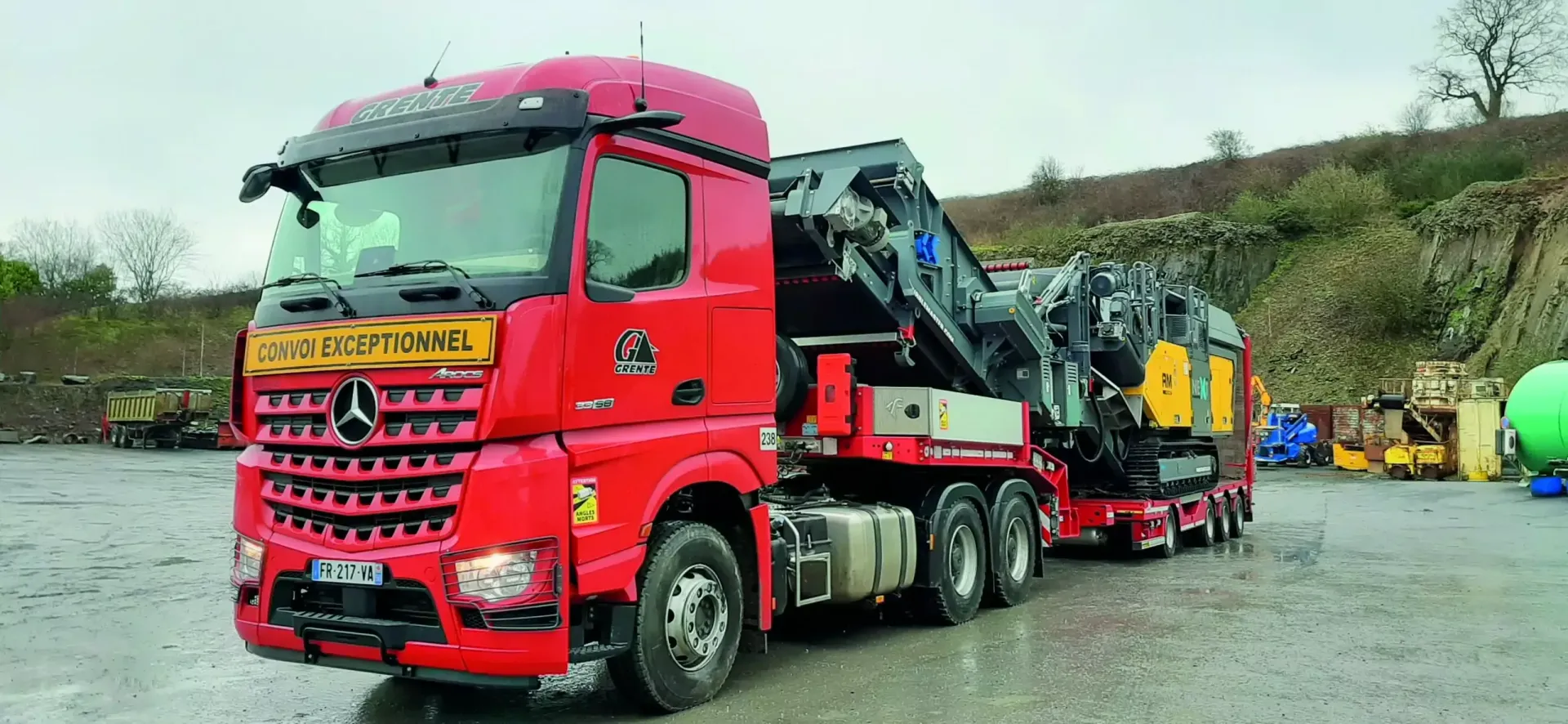 Un porte-engins aux couleurs de la société Grente SAS transportant une centrale de concassage.