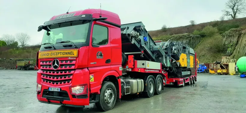 Un camion de transport exceptionnel avec une centrale de concassage sur une remorque.