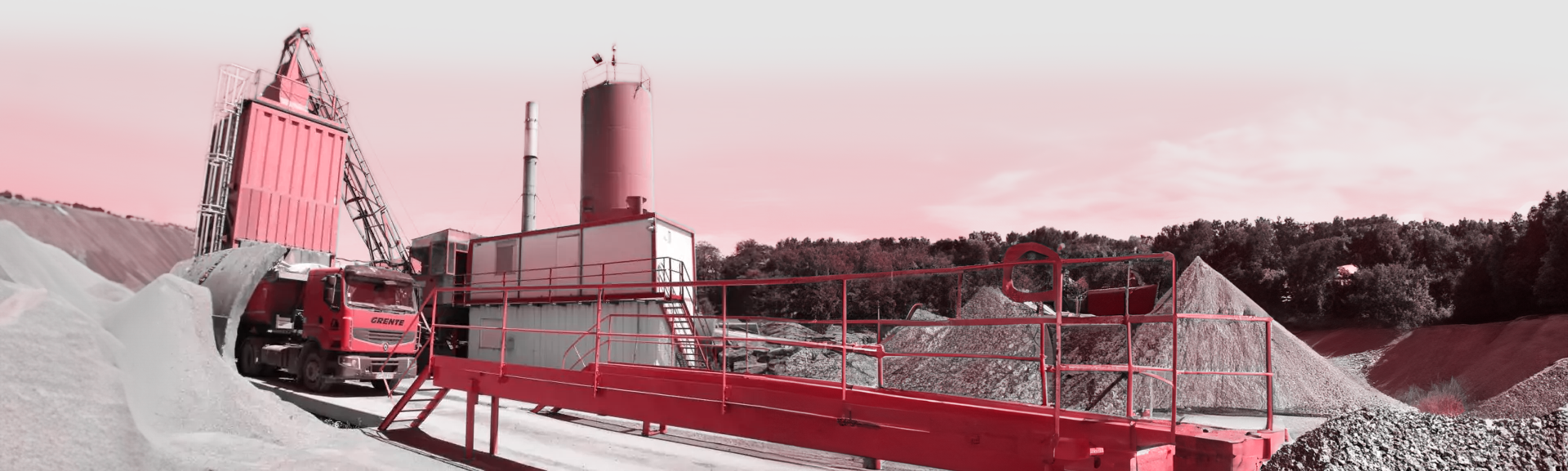 Une photo avec un filtre rouge d'un camion de chez Grente SAS au milieu d'une centrale d'enrobage.