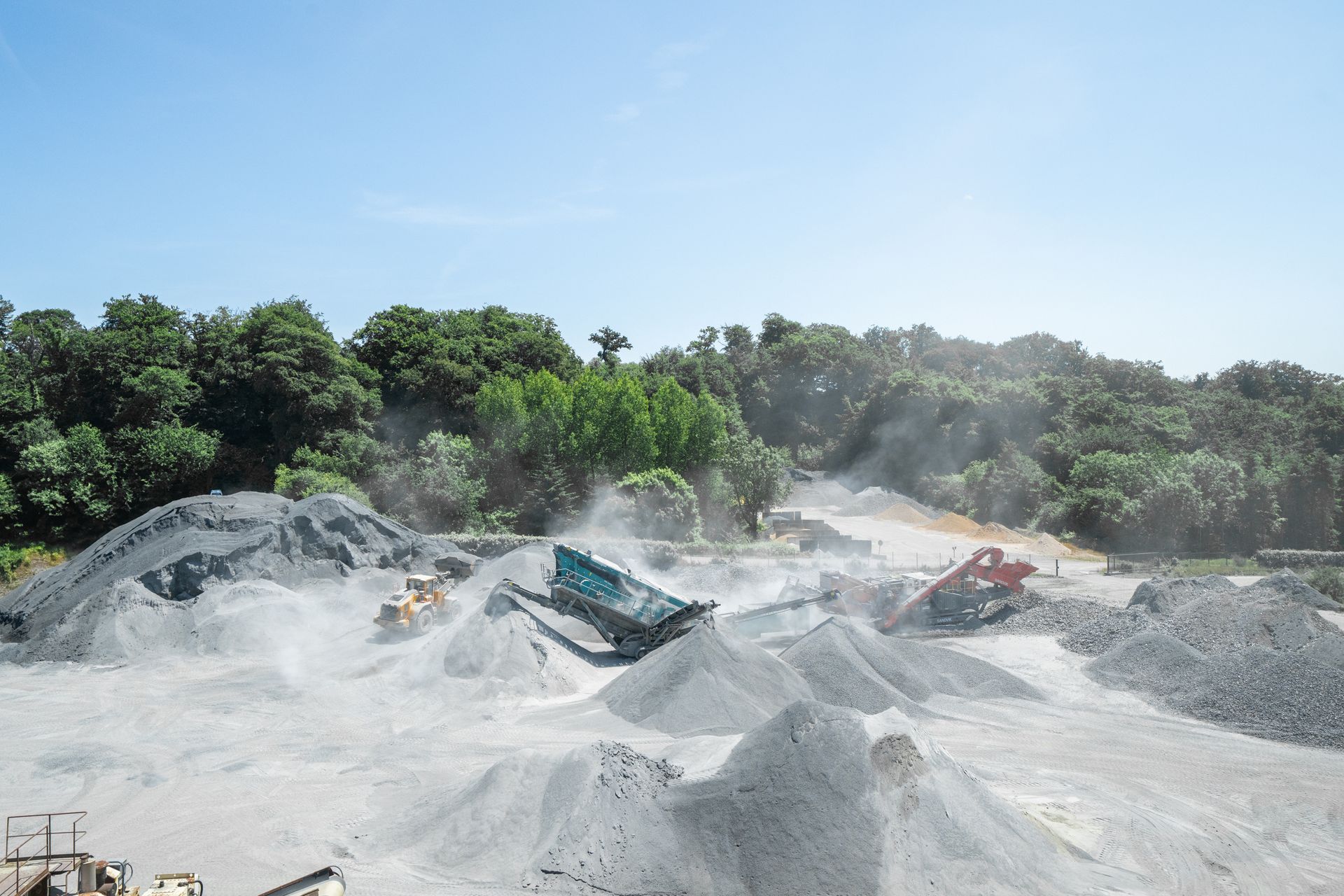 Vue d'ensemble d'une carrière avec engin de concassage et monticules de gravats.