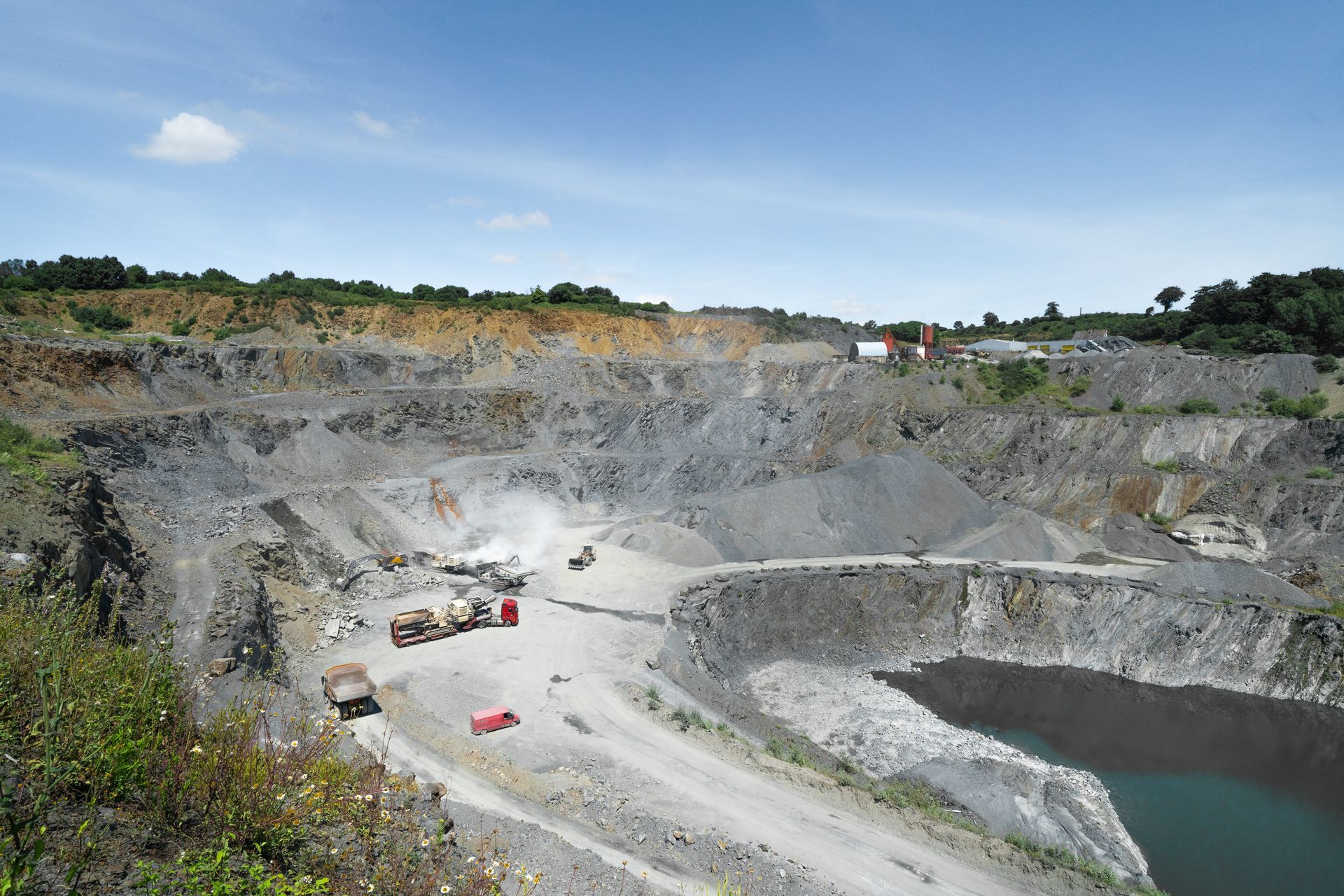 Vue d'ensemble d'une carrière avec engin de concassage et monticules de gravats.